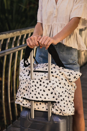 Model with polka dot beach bag and suitcase sleeve slid over suitcase 