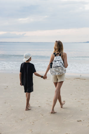 Mother and child walking on beach with Nixon backpack with multiple pockets
